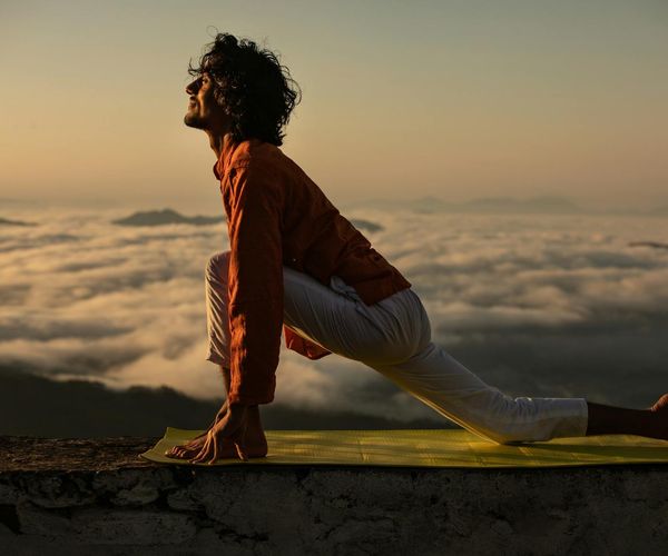 Silhouette of a man stretching against a beautiful sunrise background, representing wellness.